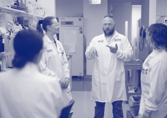 Blue duotone image of Jnana scientists having a conversation in a lab.