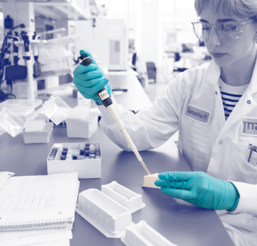 Blue duotone image of Jnana scientist in the lab with purple target encircling her gloved hand pipetting.