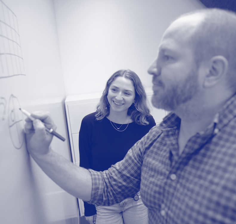 Blue duotone image of Jnana team members writing on a whiteboard.